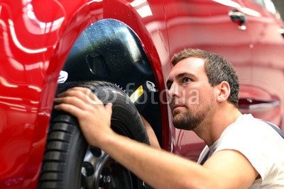 Leinwand-Bild 140 x 90 cm: "KFZ Mechaniker kontrolliert Reifen und Fahrzeug in d. Werkstatt", Bild auf Leinwand